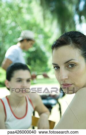 Family having cookout, woman looking over shoulder at camera View Large Photo Image Stock Image - Family having cookout, woman looking over shoulder at camera. Fotosearch