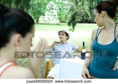 Family having meal outdoors, focus on man drinking wine View Large Photo Image Picture - Family having meal outdoors, focus on man drinking wine. Fotosearch
