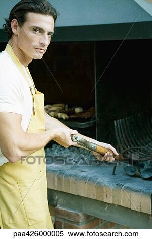 Stock Photography - Man cleaning out barbecue. Fotosearch