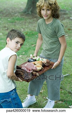 Two boys carrying tray of grilled and raw meats View Large Photo Image Stock Photo - Two boys carrying tray of grilled and raw meats. Fotosearch