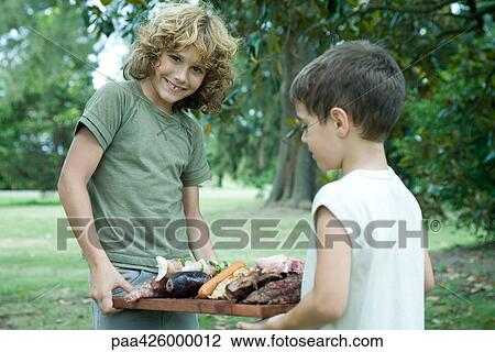 Two boys holding tray of grilled meats View Large Photo Image Stock Image - Two boys holding tray of grilled meats. Fotosearch