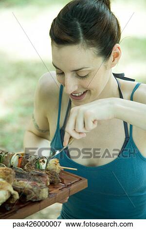 Stock Photo - Woman picking up grilled kebab. Fotosearch