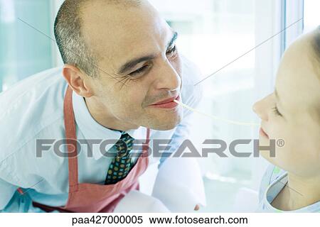 Father and daughter holding ends of noodle in mouths, smiling View Large Photo Image Stock Photography - Father and daughter holding ends of noodle in mouths, smiling. Fotosearch