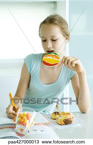 Girl doing homework and eating junk food View Large Photo Image Stock Image - Girl doing homework and eating junk food. Fotosearch