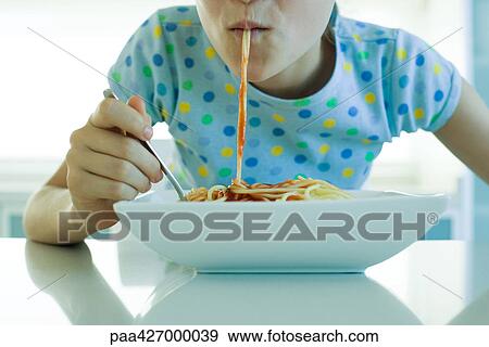 Stock Photo - Girl eating spaghetti with tomato sauce, cropped view. Fotosearch