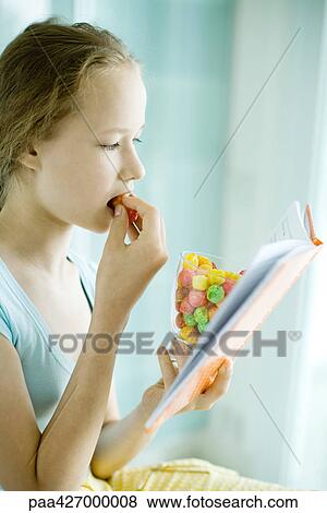 Girl reading and eating dry cereal View Large Photo Image Stock Photo - Girl reading and eating dry cereal. Fotosearch