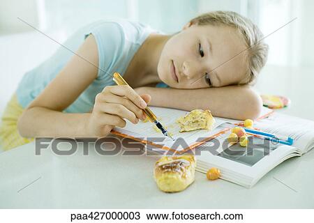 Girl sitting at table doing homework, resting head on arm, doodling, food scattered on books View Large Photo Image Stock Image - Girl sitting at table doing homework, resting head on arm, doodling, food scattered on books. Fotosearch