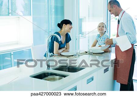 Man serving woman and girl in kitchen View Large Photo Image Stock Image - Man serving woman and girl in kitchen. Fotosearch