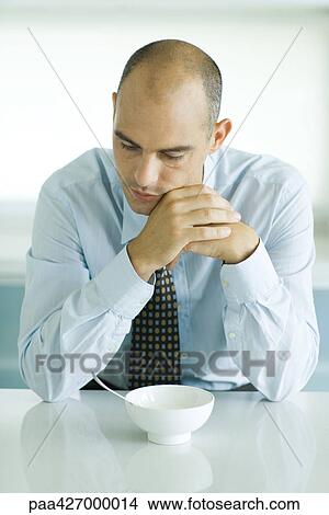 Man sitting at table with empty bowl in front of him View Large Photo Image Picture - Man sitting at table with empty bowl in front of him. Fotosearch