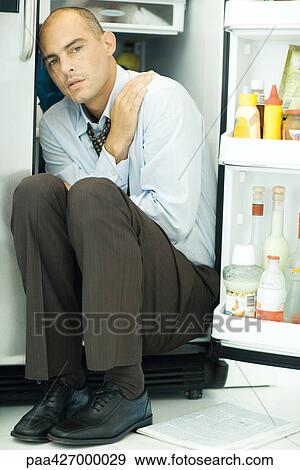 Man sitting in open refrigerator, crossing arms View Large Photo Image Stock Photo - Man sitting in open refrigerator, crossing arms. Fotosearch