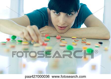Woman arranging pieces of candy on table View Large Photo Image Stock Photograph - Woman arranging pieces of candy on table. Fotosearch