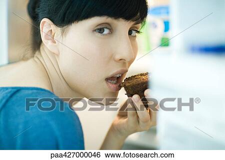 Woman eating piece of chocolate cake, looking over shoulder at camera View Large Photo Image Stock Photograph - Woman eating piece of chocolate cake, looking over shoulder at camera. Fotosearch