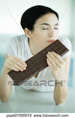Woman holding large bar of chocolate, eyes closed View Large Photo Image Stock Photo - Woman holding large bar of chocolate, eyes closed. Fotosearch