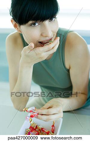Stock Photo - Young woman eating candy. Fotosearch