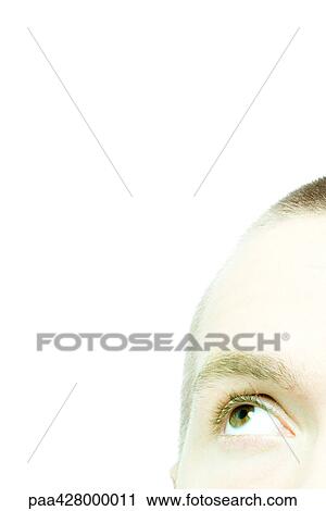 Stock Image - Young man looking up, cropped view of face. Fotosearch