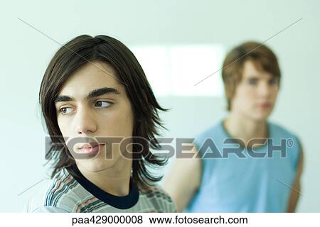 Stock Photo - Teenage boy looking away, friend in background, portrait. Fotosearch