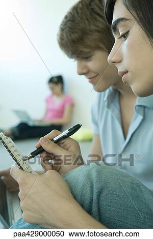 Teenage friends, focus on teen boy in foreground writing in notebook View Large Photo Image Stock Image - Teenage friends, focus on teen boy in foreground writing in notebook . Fotosearch