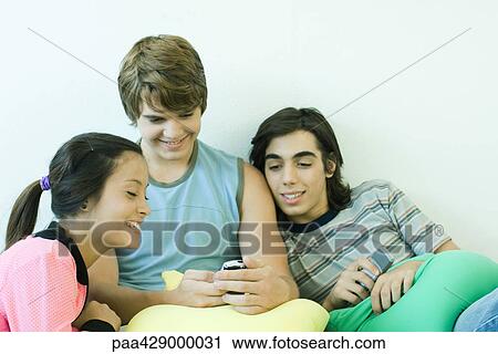 Teenage friends looking at cell phone together View Large Photo Image Stock Image - Teenage friends looking at cell phone together. Fotosearch