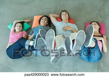 Teenage friends lying on floor with feet in the air, view from directly above View Large Photo Image Stock Image - Teenage friends lying on floor with feet in the air, view from directly above. Fotosearch