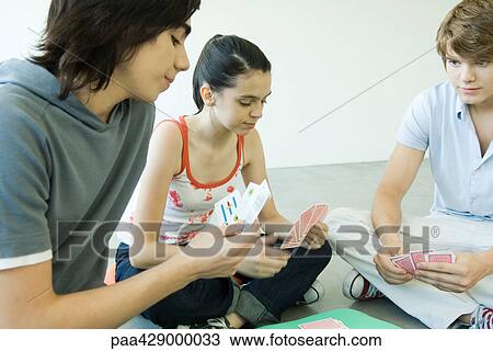 Stock Image - Teenage friends playing cards. Fotosearch