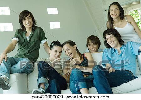 Teenage friends sitting on couch, smiling and laughing View Large Photo Image Stock Photo - Teenage friends sitting on couch, smiling and laughing. Fotosearch