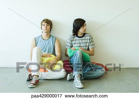 Teenage friends sitting on cushions on floor, full length View Large Photo Image Stock Photo - Teenage friends sitting on cushions on floor, full length. Fotosearch