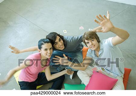 Teenage friends sitting on floor, with playing cards scattered around, smiling at camera View Large Photo Image Picture - Teenage friends sitting on floor, with playing cards scattered around, smiling at camera. Fotosearch