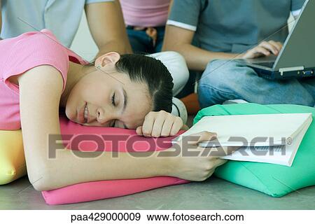 Stock Photo - Teenage friends, teen girl holding book, resting head on cushion . Fotosearch