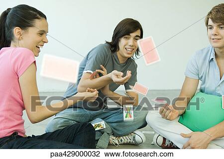Teenage friends throwing playing cards into the air View Large Photo Image Stock Image - Teenage friends throwing playing cards into the air. Fotosearch