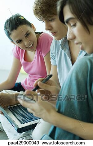 Teenage friends using laptop and taking notes View Large Photo Image Stock Photo - Teenage friends using laptop and taking notes. Fotosearch