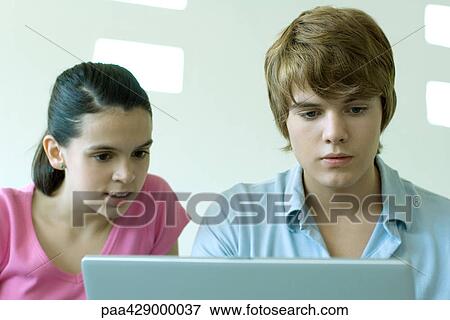 Stock Photo - Teenage friends using laptop together. Fotosearch