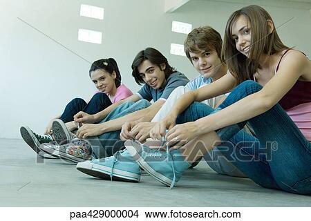 Picture - Teenage friends wearing canvas shoes, tying laces. Fotosearch