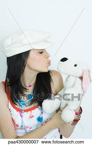Stock Photo - Teenage girl puckering lips at stuffed animal, portrait. Fotosearch