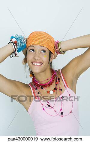Teenage girl wearing lots of jewelry, hands behind head, looking up, smiling, portrait View Large Photo Image Stock Photo - Teenage girl wearing lots of jewelry, hands behind head, looking up, smiling, portrait. Fotosearch