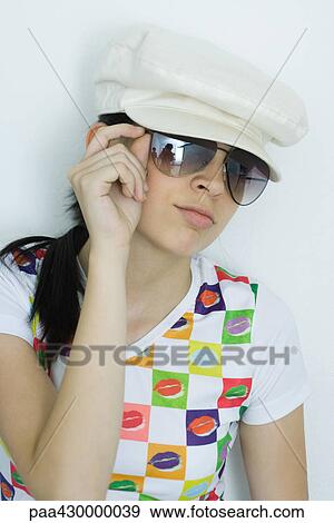 Stock Photo - Teenage girl wearing sunglasses and cap, portrait. Fotosearch