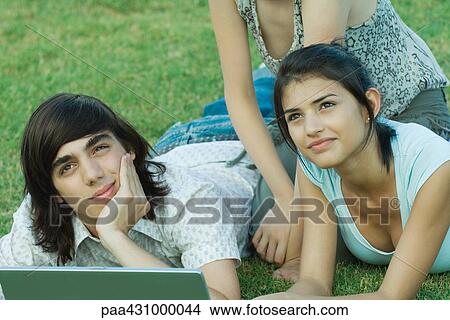 Group of young friends lying on grass using laptop View Large Photo Image Picture - Group of young friends lying on grass using laptop. Fotosearch