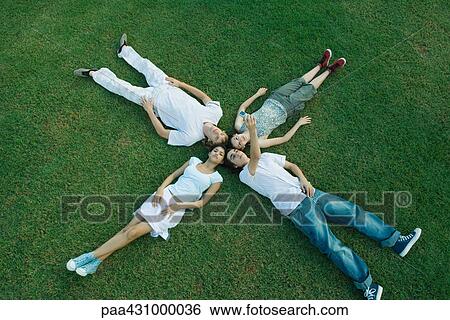 Group of young friends lying on grass, heads together View Large Photo Image Stock Photograph - Group of young friends lying on grass, heads together. Fotosearch