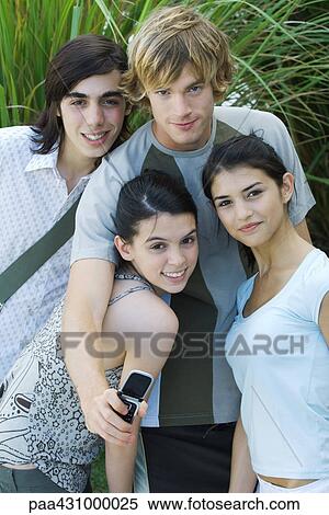Group of young friends, one holding cell phone, portrait View Large Photo Image Stock Photography - Group of young friends, one holding cell phone, portrait. Fotosearch
