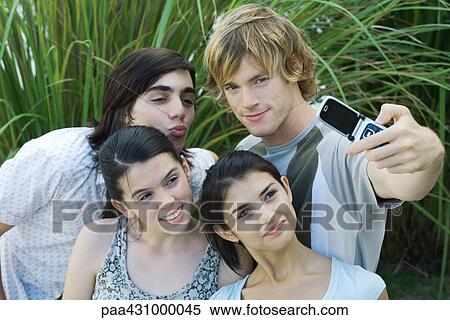 Group of young friends posing while man takes photo with cell phone View Large Photo Image Stock Photography - Group of young friends posing while man takes photo with cell phone. Fotosearch