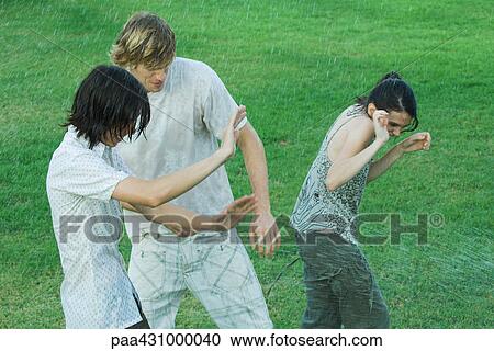Group of young friends standing in water spray, getting wet View Large Photo Image Stock Image - Group of young friends standing in water spray, getting wet. Fotosearch