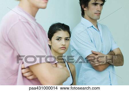 Picture - Group of young friends standing side by side, focus on young woman looking at camera. Fotosearch