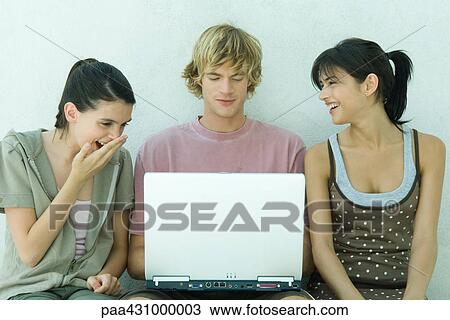 Stock Image - Group of young friends using laptop. Fotosearch