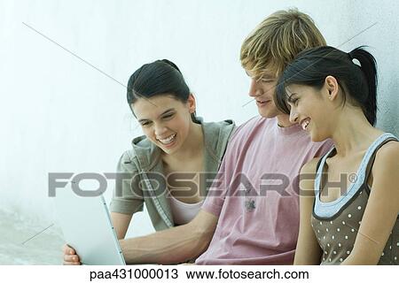 Group of young friends using laptop together View Large Photo Image Stock Image - Group of young friends using laptop together. Fotosearch