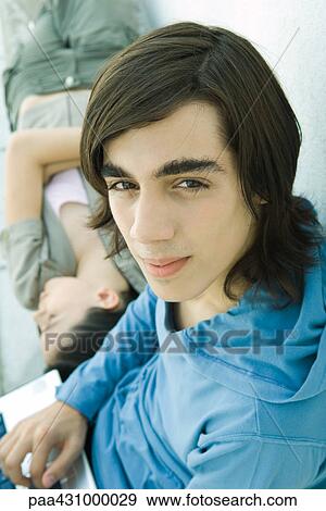 Teen boy looking at camera while female friend lies on back View Large Photo Image Stock Photo - Teen boy looking at camera while female friend lies on back. Fotosearch