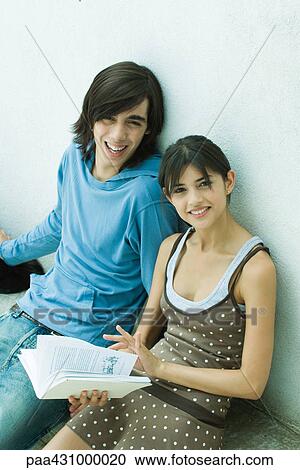 Young couple sitting side by side on bench, woman holding book View Large Photo Image Stock Image - Young couple sitting side by side on bench, woman holding book. Fotosearch