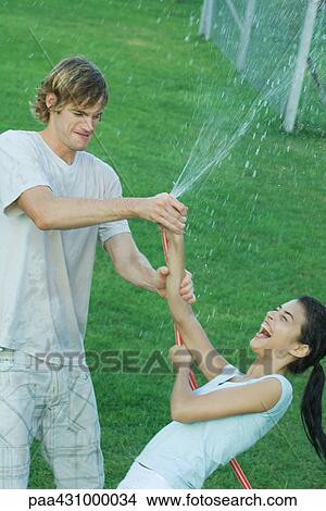 Young friends playing with garden hose, getting wet View Large Photo Image Picture - Young friends playing with garden hose, getting wet. Fotosearch