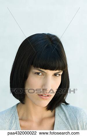 Stock Image - Woman scowling at camera, head and shoulders, portrait. Fotosearch