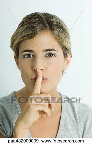 Stock Photo - Woman with finger over lips, head and shoulders, portrait. Fotosearch