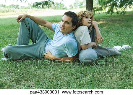 Boy and father sitting back to back on grass View Large Photo Image Stock Image - Boy and father sitting back to back on grass. Fotosearch