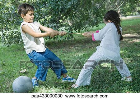 Stock Image - Boy and girl playing tug-of-war. Fotosearch